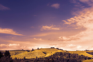 Green hilly landscape and blue sky during summer.