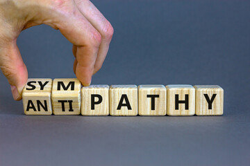 From antipathy to sympathy. Businessman turns cubes and changes the word 'antipathy' to 'sympathy'. Beautiful grey background. Copy space. Psychological and antipathy or sympathy concept.