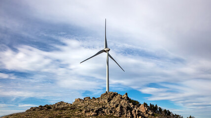 Wind turbine, renewable energy on a rocky hill.
