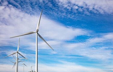 Wind turbines, renewable energy on  blue cloudy sky background. Wind farm