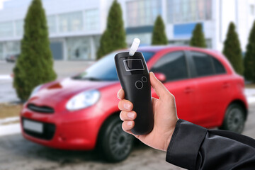 Police officer with breathalyzer near car outdoors. Alcohol consumption while driving