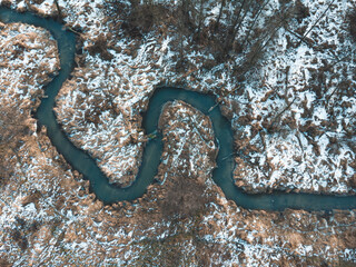 Wonderful river with many winding and meandering bends in the Polish countryside seen from a drone, snowy landscape in mazowieckie. Forest nature. Głuchów. abstract