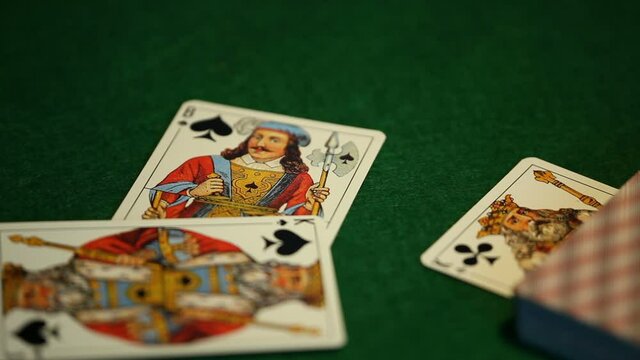 card player throws playing cards of spades on the green table close-up