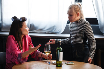 Alcoholism in family problem. Daughter aguring with her mother about drinking wine. Two people, woman and teenage girl quarrel in the kitchen. A depressed female is addicted to alcohol at home.
