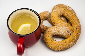 delicious hot tea with honey and lemon and pretzel on white background