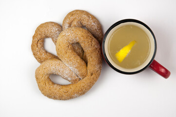 delicious hot tea with honey and lemon and pretzel on white background