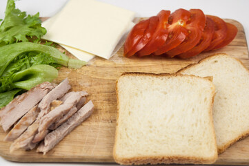 Sandwich with ham, cheese, tomatoes, lettuce, and toasted bread. Above view on white background.