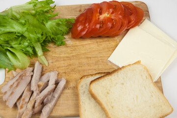 Sandwich with ham, cheese, tomatoes, lettuce, and toasted bread. Above view on white background.