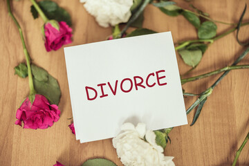 Paper with divorce word on a floor with withered flowers. Concept.