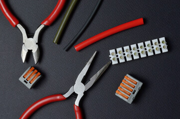 tools for working with electricity, terminal blocks and heat shrink tubes lie on a dark background.