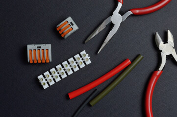 tools for working with electricity, terminal blocks and heat shrink tubes lie on a dark background.