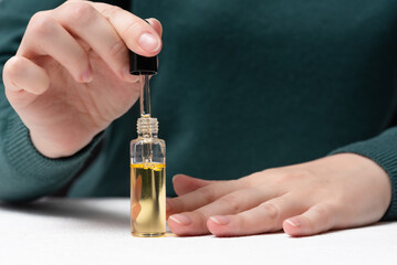 Woman is applying a cuticle oil on her fingernails close up.