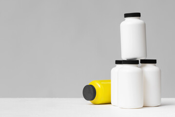 Blank white jars for food supplement on the table front view background.