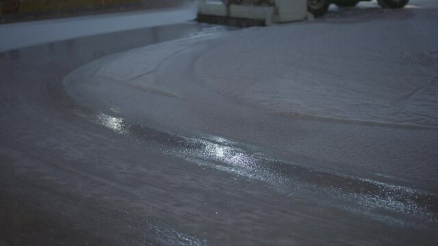Outdoor public skating rink with ice resurfacing machine. close-up of ice treatment and wet footprint