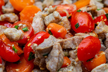 Fried juicy pieces of pork meat, tomatoes, garlic, green onions and spices. Shallow depth of field.Top view. Macro