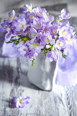 Obraz premium Freesia flowers in a vase on a table. Soft focus. Lovely bunch of flowers.