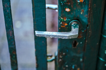 Wet door handle on a green metal gate