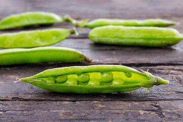 Green pea pods on a wooden background, harvest of peas