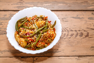 Vegetables with chicken fillet in pan-Asian sauce with sesame seeds on a wooden table in a plate kopy place.