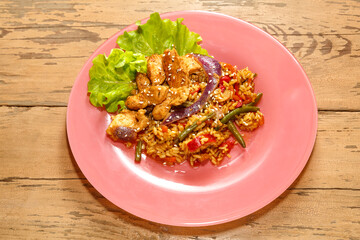 Vegetables with chicken meat in pan-Asian sauce with sesame seeds on lettuce leaves on a wooden table in a plate copy the place.