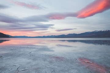 Beautiful pink sunrise reflecting in wet salt field of Death Valley National Park, California
