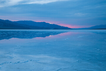 Pink and blue sunset at wet salt fields of Badwater in Death Valley National Park