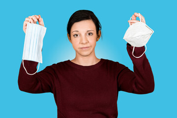 Junges M&auml;dchen h&auml;lt FFP2 Maske und Mund-Nasen-Schutz und schaut verwundert