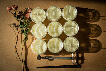 wooden wick candles. Handmade candle from paraffin and soy wax in glass with flowers and leaf on craft background. Let flay. Candle making. Top view.