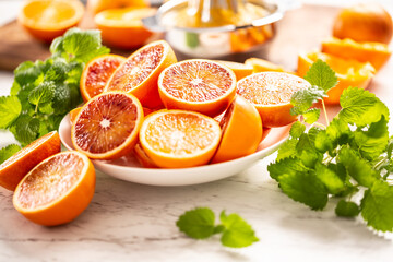 Blood sicilian oranges sliced on white plate with fresh melissa