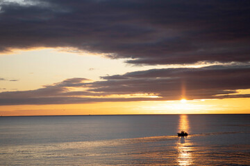 Fishing boat sailing at sunrise
