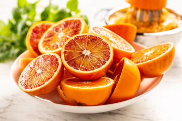 Blood sicilian oranges sliced on white plate with fresh melissa