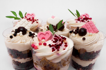 Sweet small homemade trifle dessert with custard, chocolate, nuts and fruits and decorations and cream cheese.