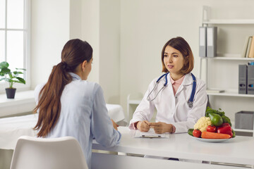 Nutrition expert talking to client about health problems and importance of eating healthy food. Doctor, nutritionist or dietitian discussing treatment with young woman and making individual diet plan