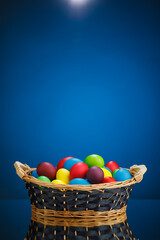 Fototapeta na wymiar Easter color eggs in festive gift basket, blue background