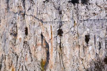 background - the surface of a huge cliff with a destroyed hanging path on it
