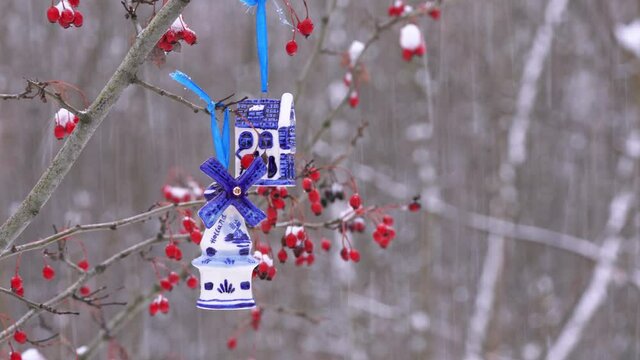 Blue ceramic Christmas toy bought in Amsterdam hangs on a branch