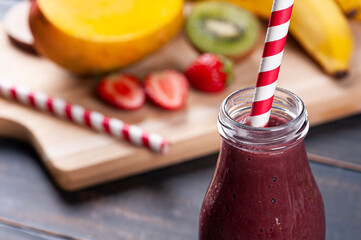 .Delicious açaí smoothie in a bottle with tropical fruits in the background