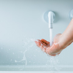 Fototapeta premium hand under the faucet with flowing water splash