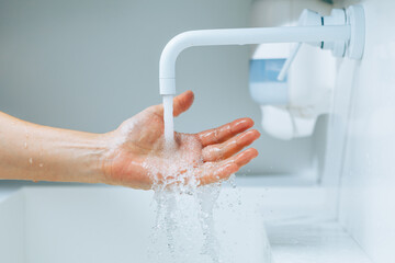 hand under the faucet with flowing water splash