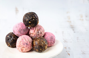 Homemade pink matcha dragon fruit energy balls, top view, white wood healthy sweets made of nuts and date, prunes, sesame, cashew nuts, Pine nuts. Concept vegeterian diet candy brain food. Copy space.