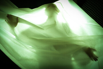 Green light shines through the fabric against a human background