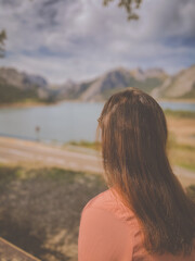 Girl sitting at the "best bench in Leon", Spain. The bench overlooks the Riano reservoir in Northern Spain. Yordas Peak towers over Riano, the Cantabrian Mountains, Castile-Leon region.