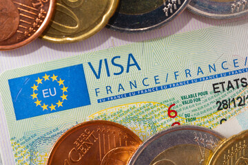 Schengen visa in the passport with a few coins. Issued by the French Embassy. This sample of the Schengen visa has been put into circulation since 2019. 
