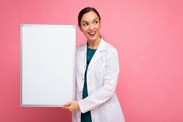 Portrait of attractive pretty young positive brunette woman wearing medical white coat holding...