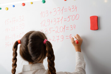 Schoolgirl counting mathematical equations on the board. Secondary school learner is good at math, doing the task easily