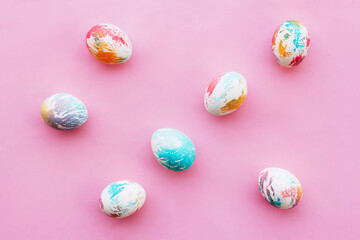 abstractly painted in different colors seven easter eggs on a pink background