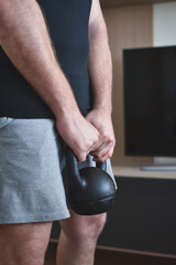 Personal trainer men hanging a kettlebell for a lesson at home
