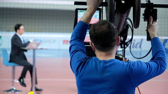 A cameraman uses a camera jib on a television show featuring a young male and female presenter. Sports News.