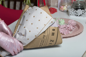 Woman makes a marshmallow bouquet. Marshmallow tulips are collected in a bouquet and wrapped in craft paper.