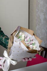 Woman makes a marshmallow bouquet. Marshmallow tulips are collected in a bouquet and wrapped in craft paper.
